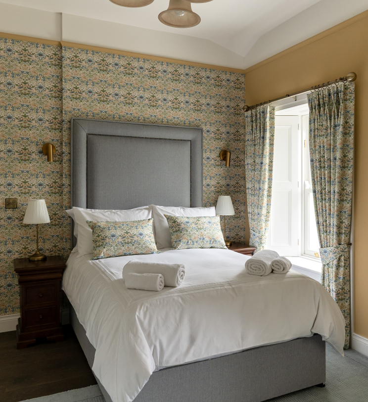 A yellow bedroom with a double bed and a patterned wall.