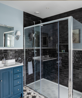 A light blue bathroom with black tiles.