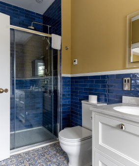 A bathroom with blue tiles and yellow walls.
