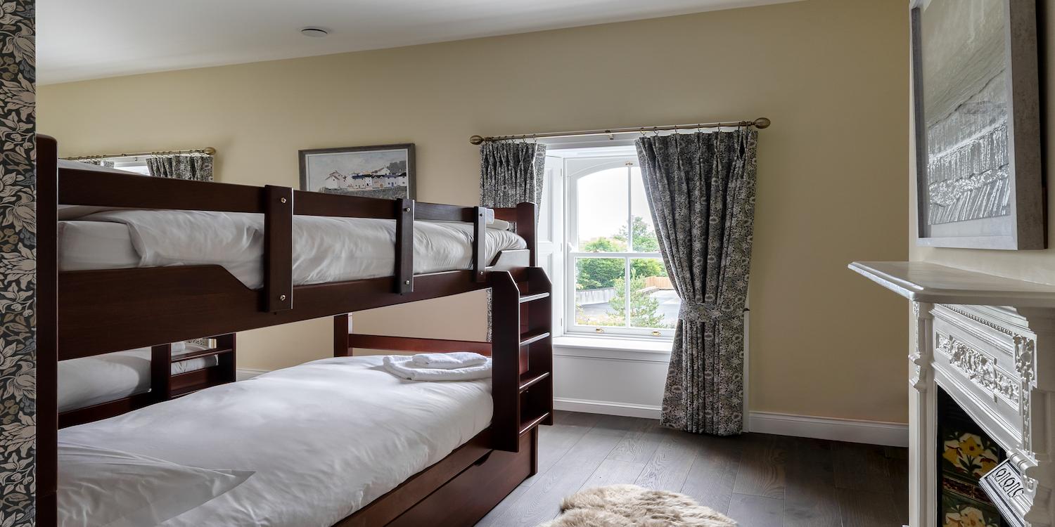 A yellow bedroom with two bunk bed and a patterned wall.