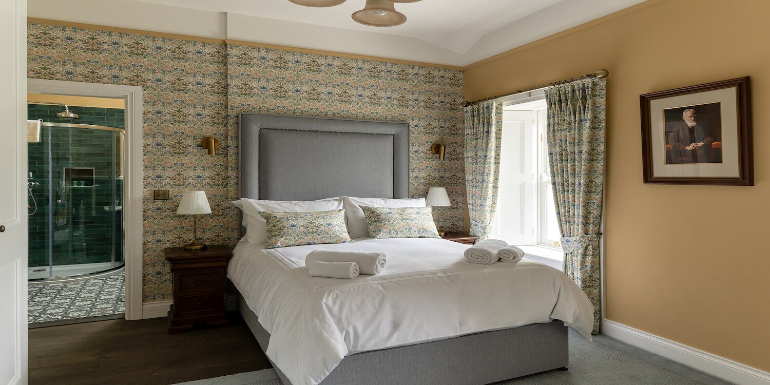 A yellow bedroom with a double bed and a patterned wall.