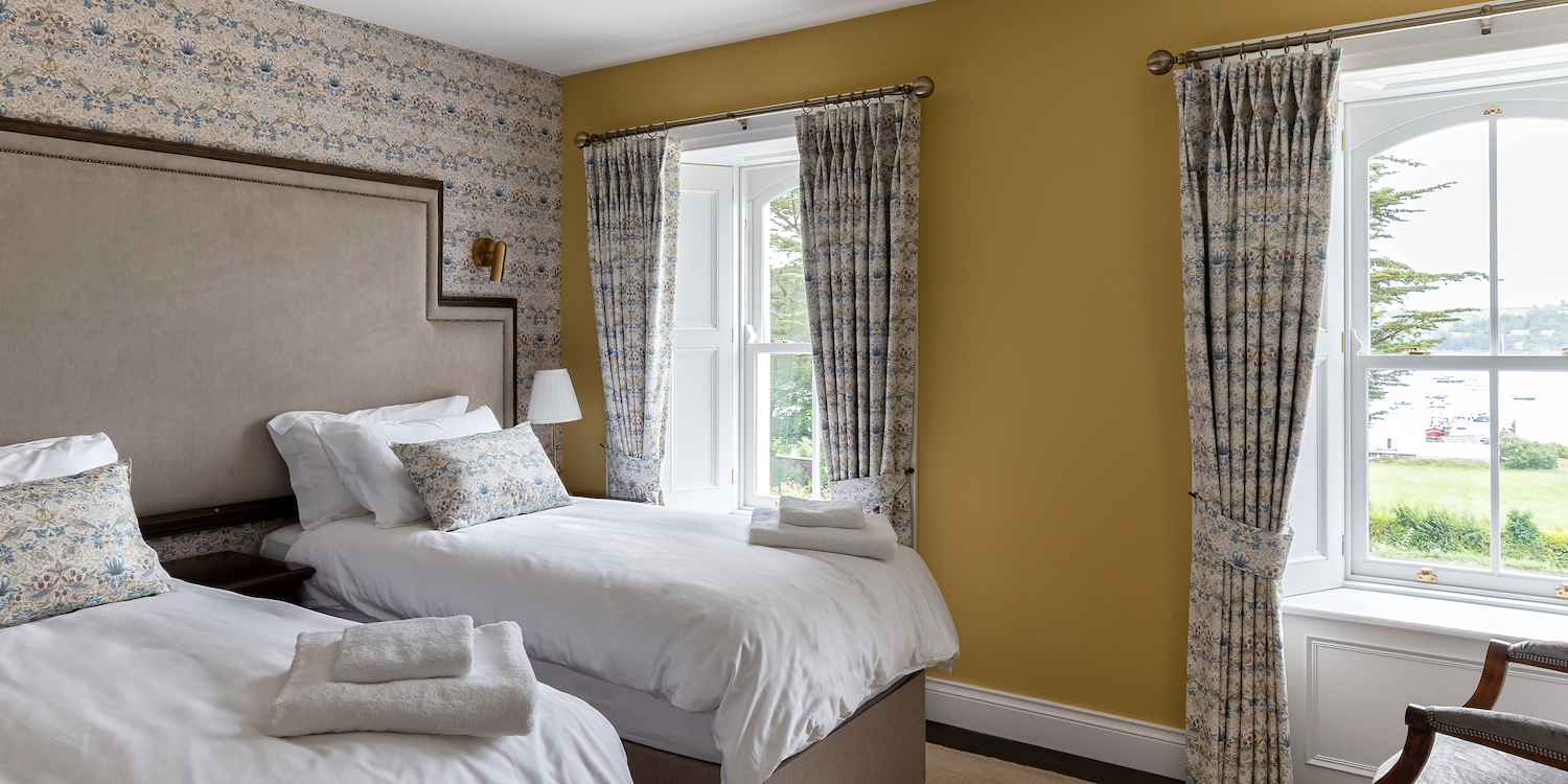 A yellow bedroom with two single beds and a patterned wall.