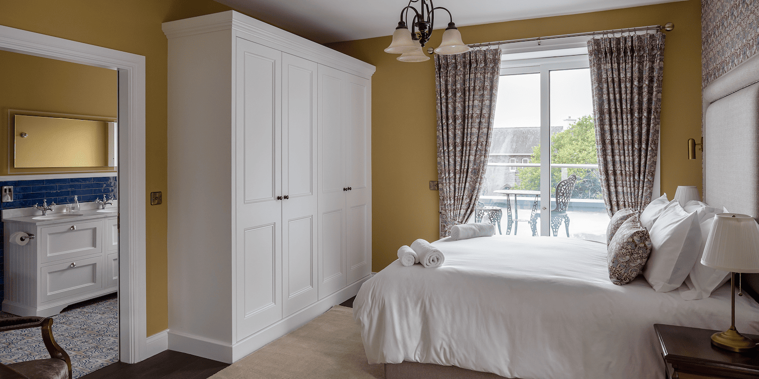 A yellow bedroom with a double bed and a white closet.