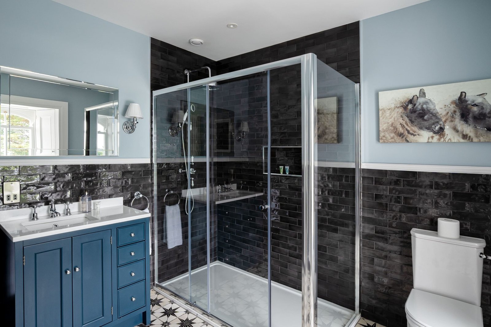A bathroom with black tiles and a light blue wall.