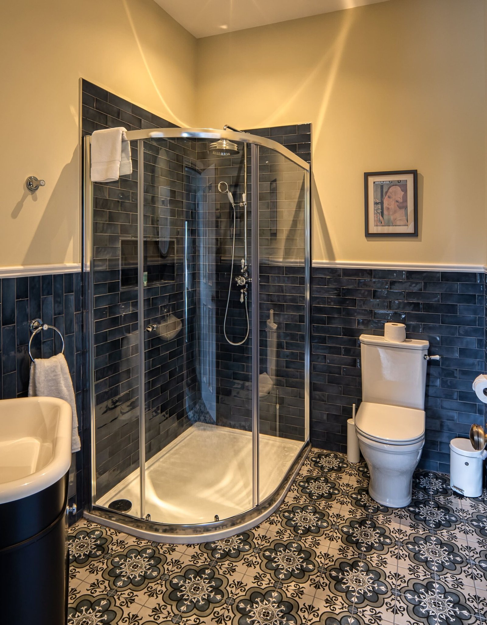 A bathroom with a yellow wall and blue tiles.