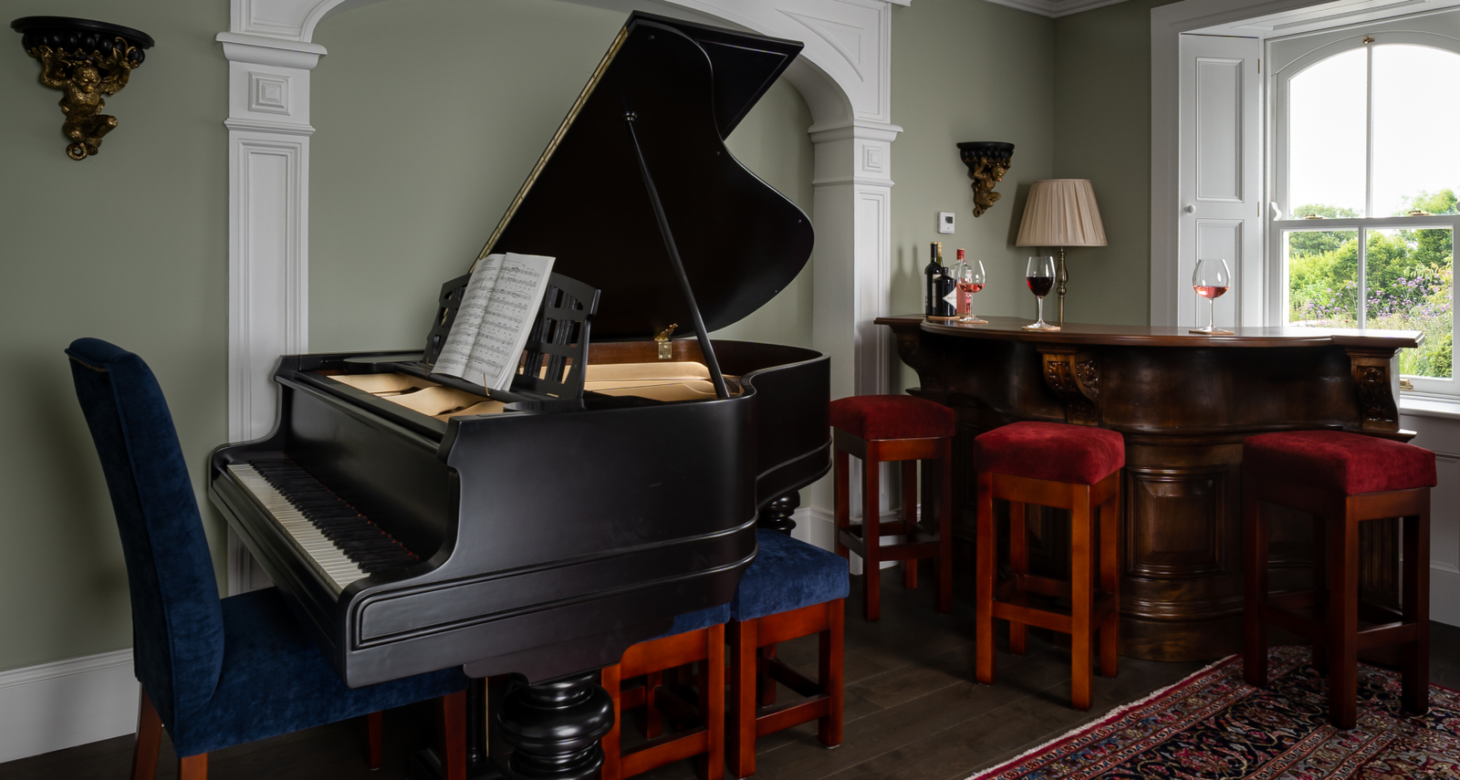 A piano in an olive green room with dark brown wooden flooring.