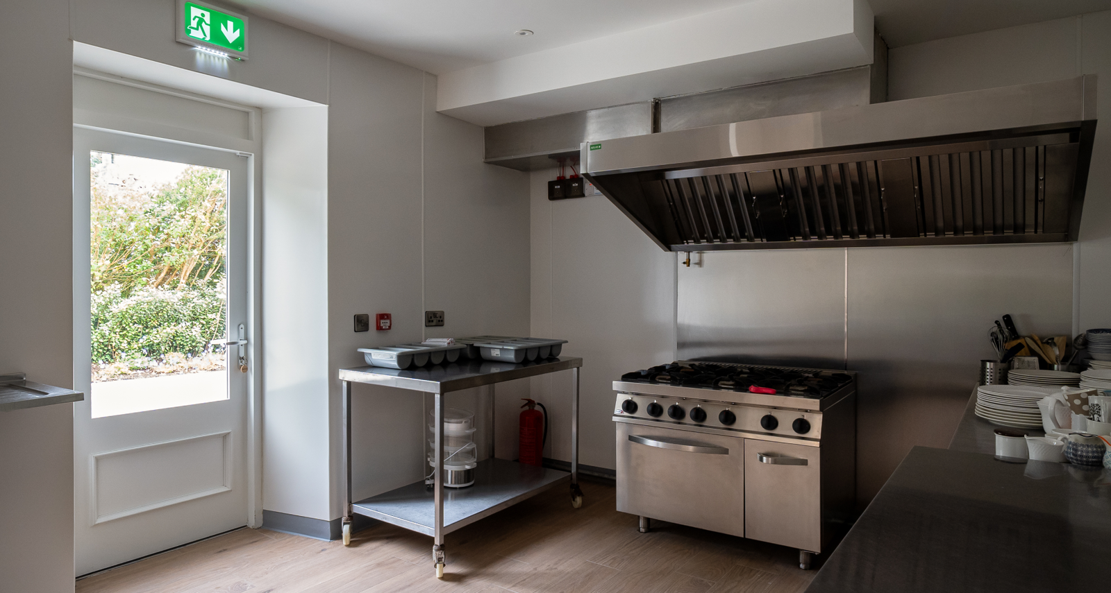 A commercial kitchen with stainless steel appliances and an exit door.