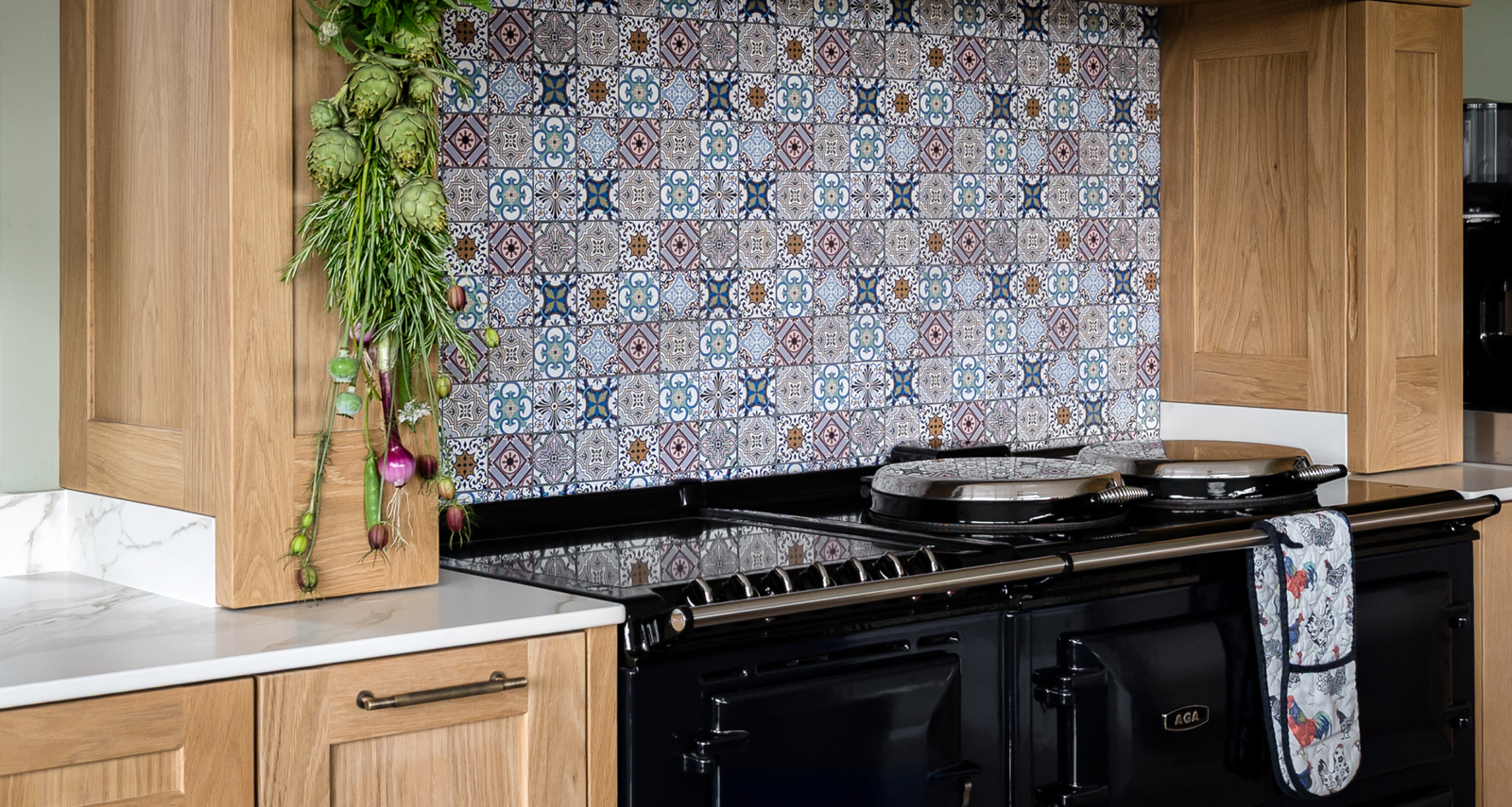 A black kitchen range stove surrounded by light wood cabinets and a patterned tile backsplash.