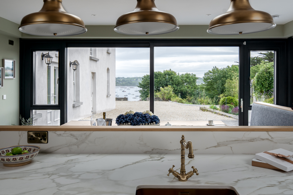 A white kitchen with a window overlooking the outdoors.
