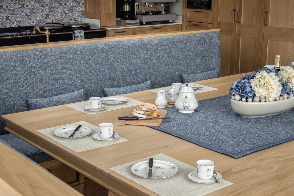 A kitchen table with plates, cups and cutlery.