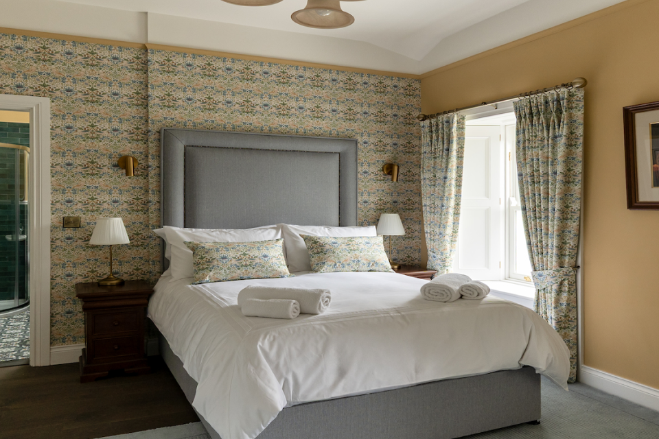 A yellow bedroom with a double bed and a patterned wall.