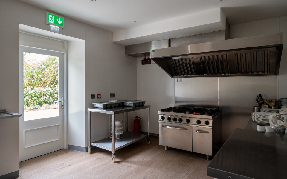 A commercial kitchen with stainless steel appliances and an exit door.