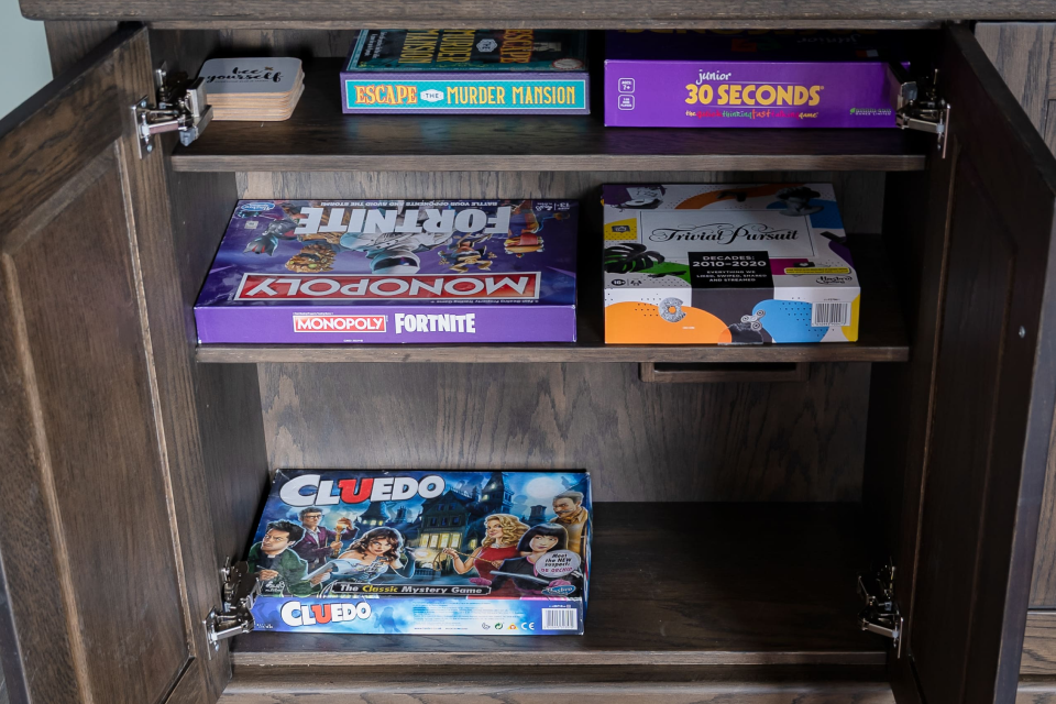 Board games in a dark wooden cabinet.