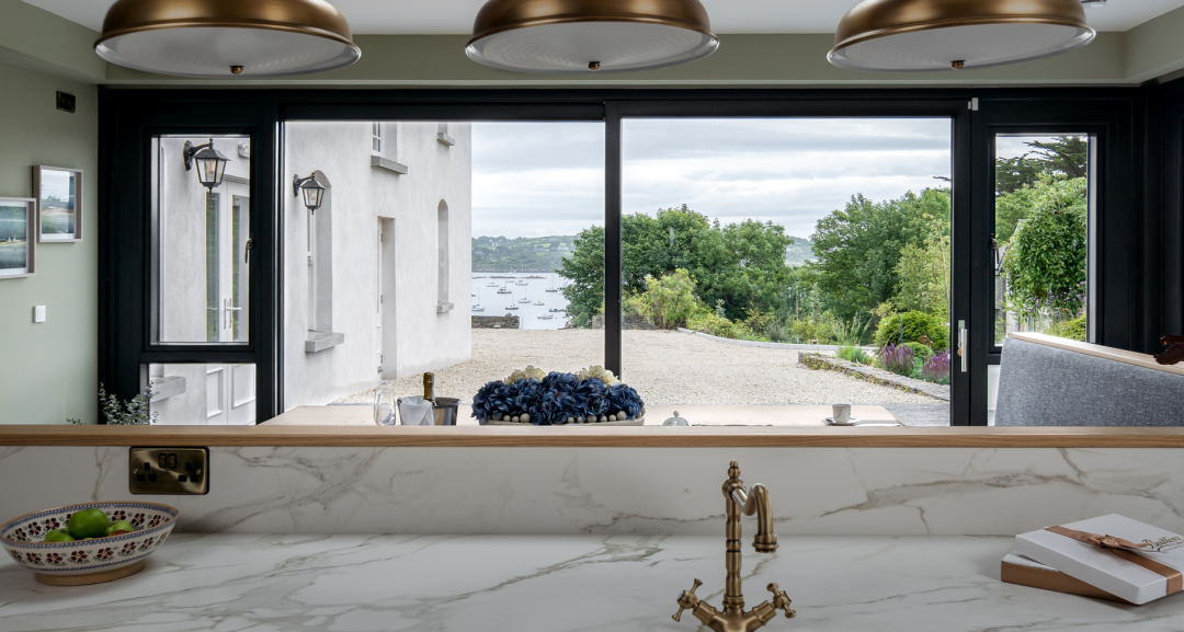 A white kitchen with a window overlooking the outdoors.