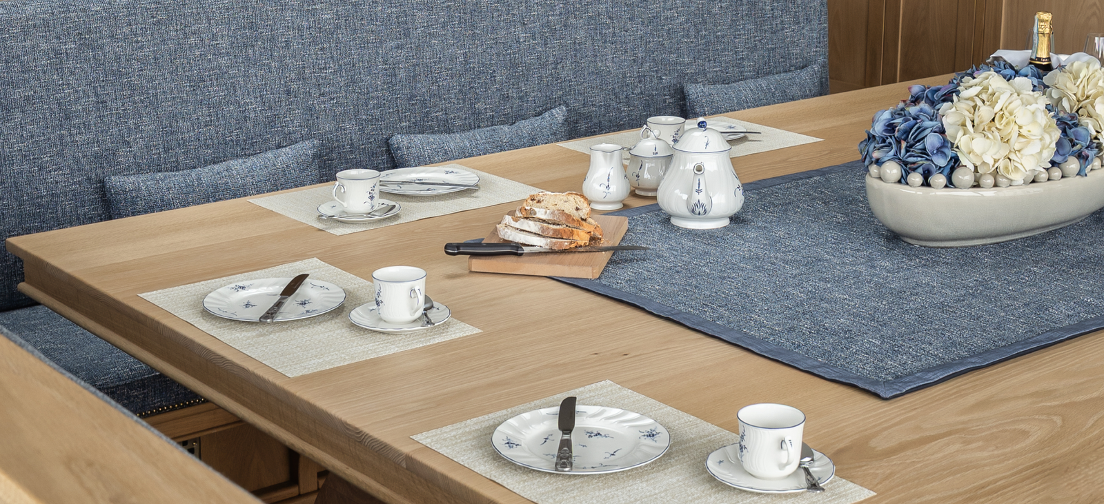 A kitchen table with bread on a wooden cutting board.
