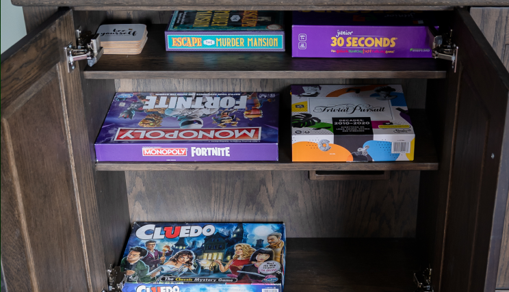 Board games in a dark wooden cabinet.