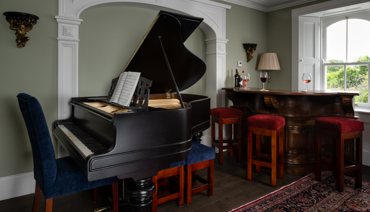 A piano in an olive green room with dark brown wooden flooring.