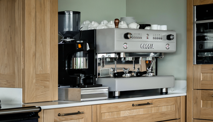 A light brown kitchen viewing a grey and black coffee machine.