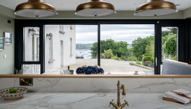 A white kitchen with a window overlooking the outdoors.